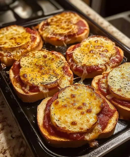 A plate of mini pizza bagels served as a party snack with extra sauce on the side