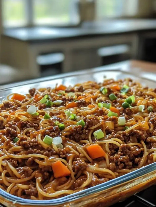 A wide shot of a skillet filled with Mongolian beef noodles, topped with fresh green onions and sesame seeds.