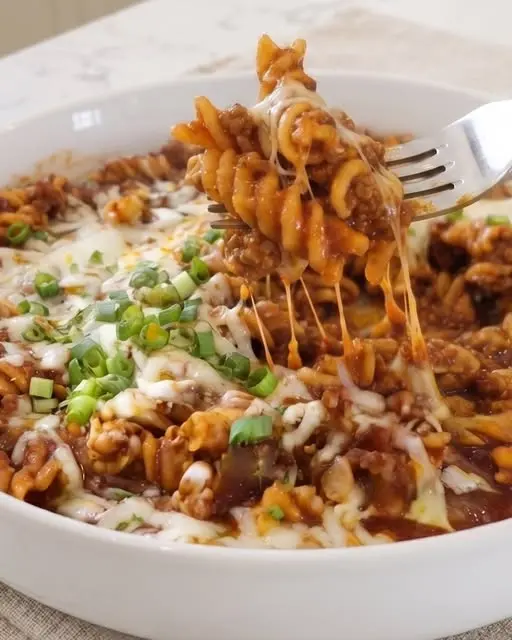 Finished enchilada pasta garnished with avocado and cilantro in a skillet