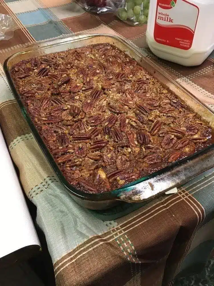 a scoop of pecan pie cobbler in a bowl topped with melting vanilla ice cream