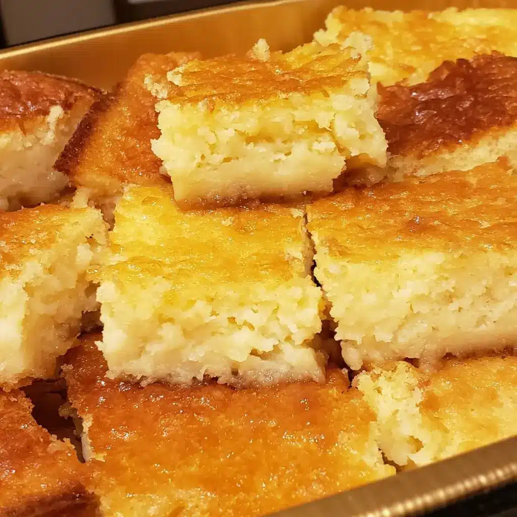 Sliced pineapple cake bars served on a white plate with a dusting of powdered sugar