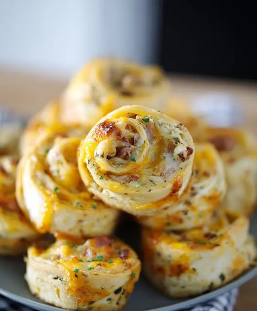 Freshly baked pizza pinwheels served on a platter with dipping sauce.