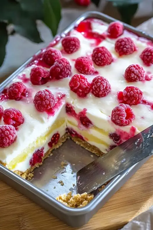 A plate of sliced raspberry cheesecake bars with a beautiful red marble swirl.