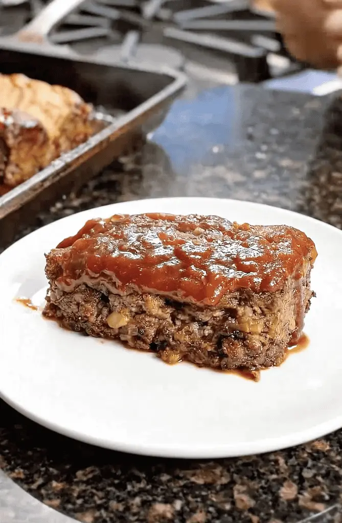 Sliced sheet pan meatloaf served with roasted potatoes and green beans