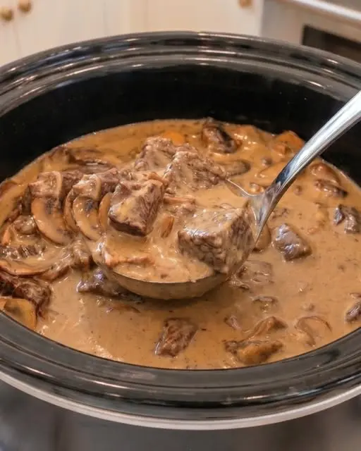 A bowl of creamy beef stroganoff served over wide egg noodles with a garnish of fresh parsley