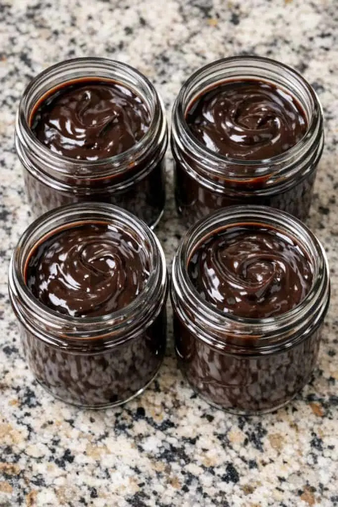 Warm hot fudge being drizzled over vanilla ice cream