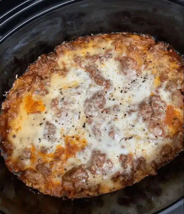 A plated slice of slow cooker lasagna with melted cheese and fresh basil garnish