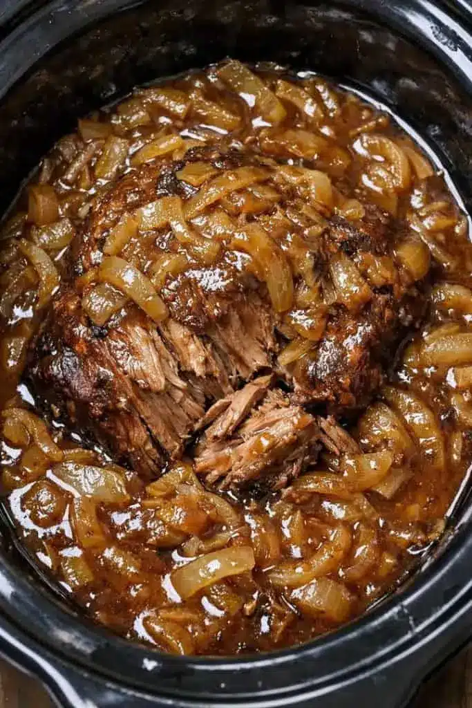 A serving of french onion soup pot roast topped with melted cheese and a toasted baguette slice