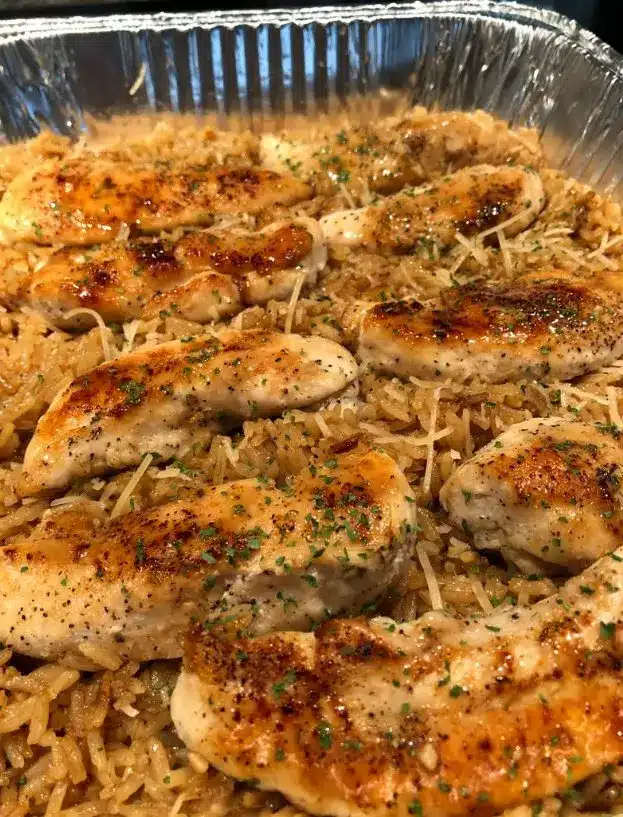 Plated garlic parmesan chicken and rice garnished with extra cheese and parsley