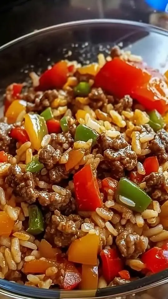The finished ground beef and vegetable skillet meal garnished with fresh herbs and served with a side of rice.