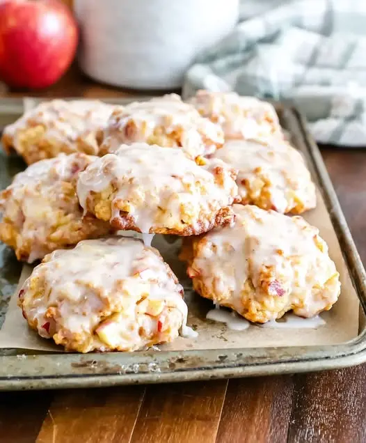 A stack of golden apple fritters with a thick vanilla glaze dripping down the sides