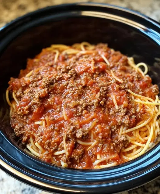 Slow cooker spaghetti sauce served over al dente pasta with parmesan cheese