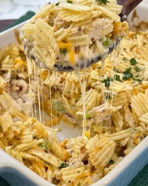 The finished hot chicken salad casserole served in a bowl with a side of greens.