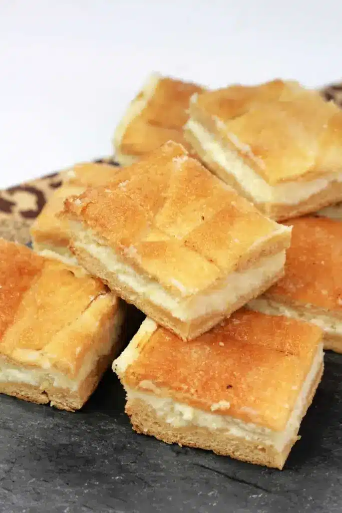 A close up of a lemon cream cheese dessert bar showing the distinct layers