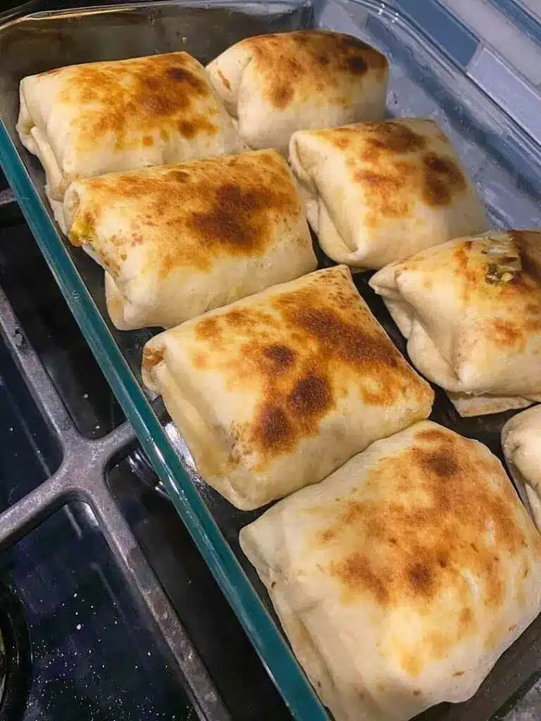 A stack of crispy cheesy pocket tacos served with dipping sauce and lime