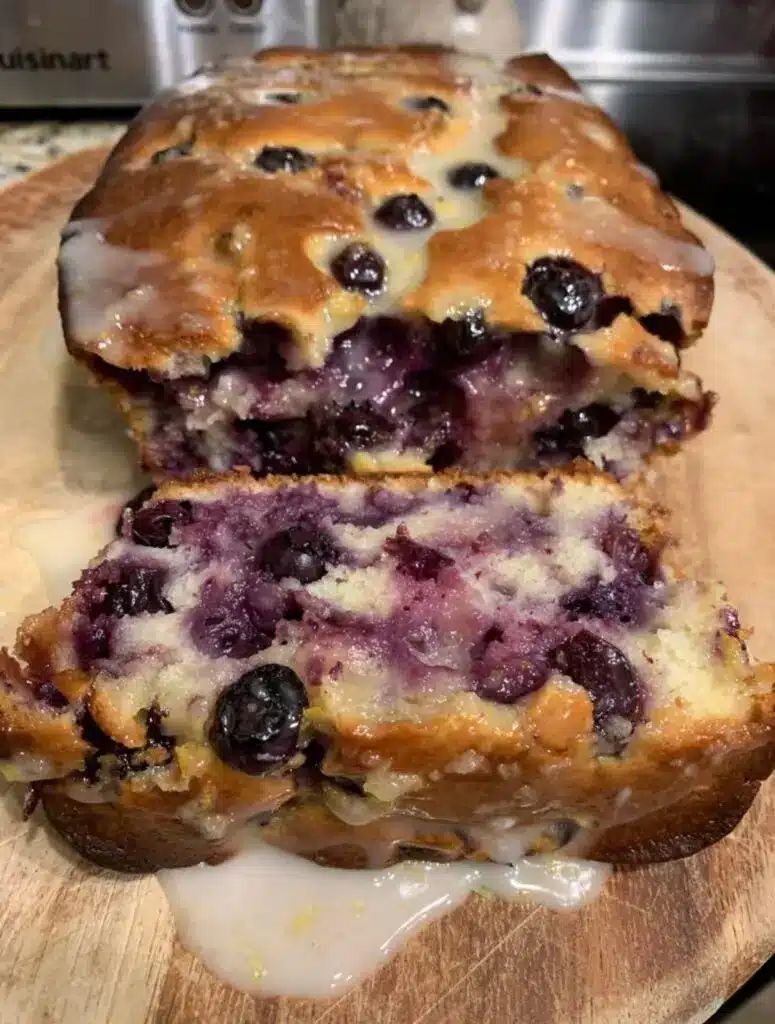 A sliced lemon blueberry loaf on a wooden serving board