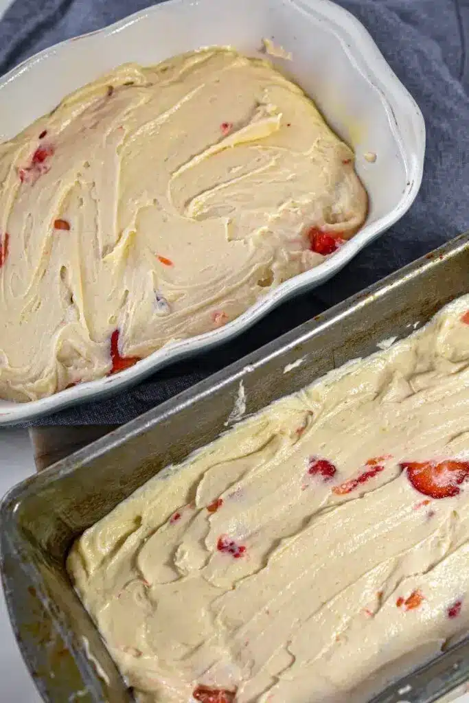 A sliced moist strawberry pound cake on a white plate with fresh berries