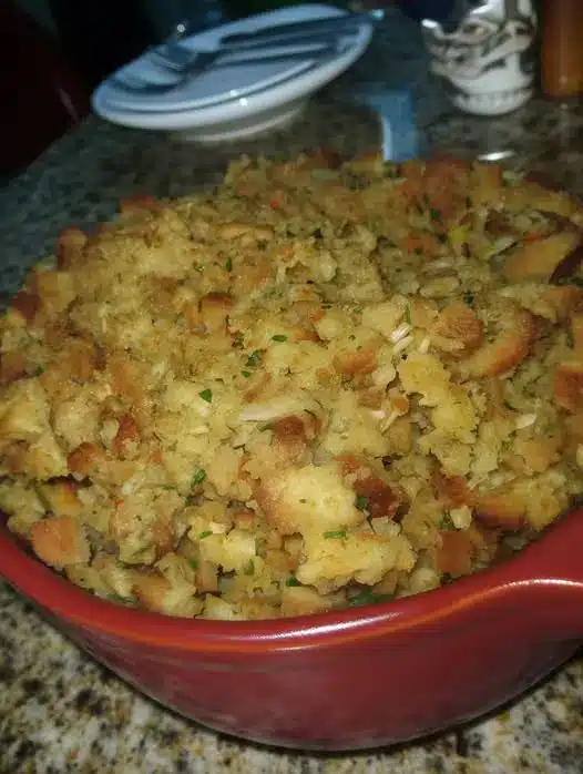 A single serving of bread pudding on a white plate with a drizzle of warm sauce.