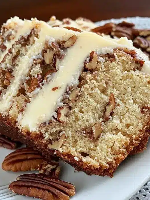 Sliced pecan cream cheese bread served on a plate with a cup of coffee nearby.