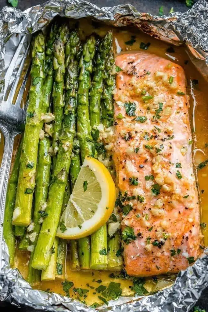 Cooked salmon and asparagus on a sheet pan with roasted lemon slices and herbs