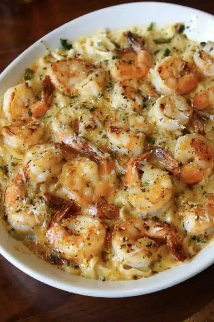 A serving of golden brown shrimp scampi pasta bake on a white plate