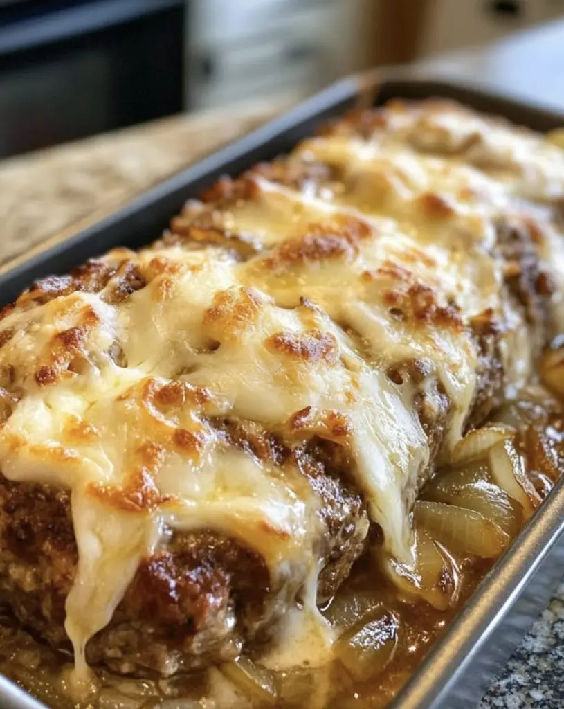 A slice of slow cooker french onion meatloaf showing the juicy interior and melted cheese topping.