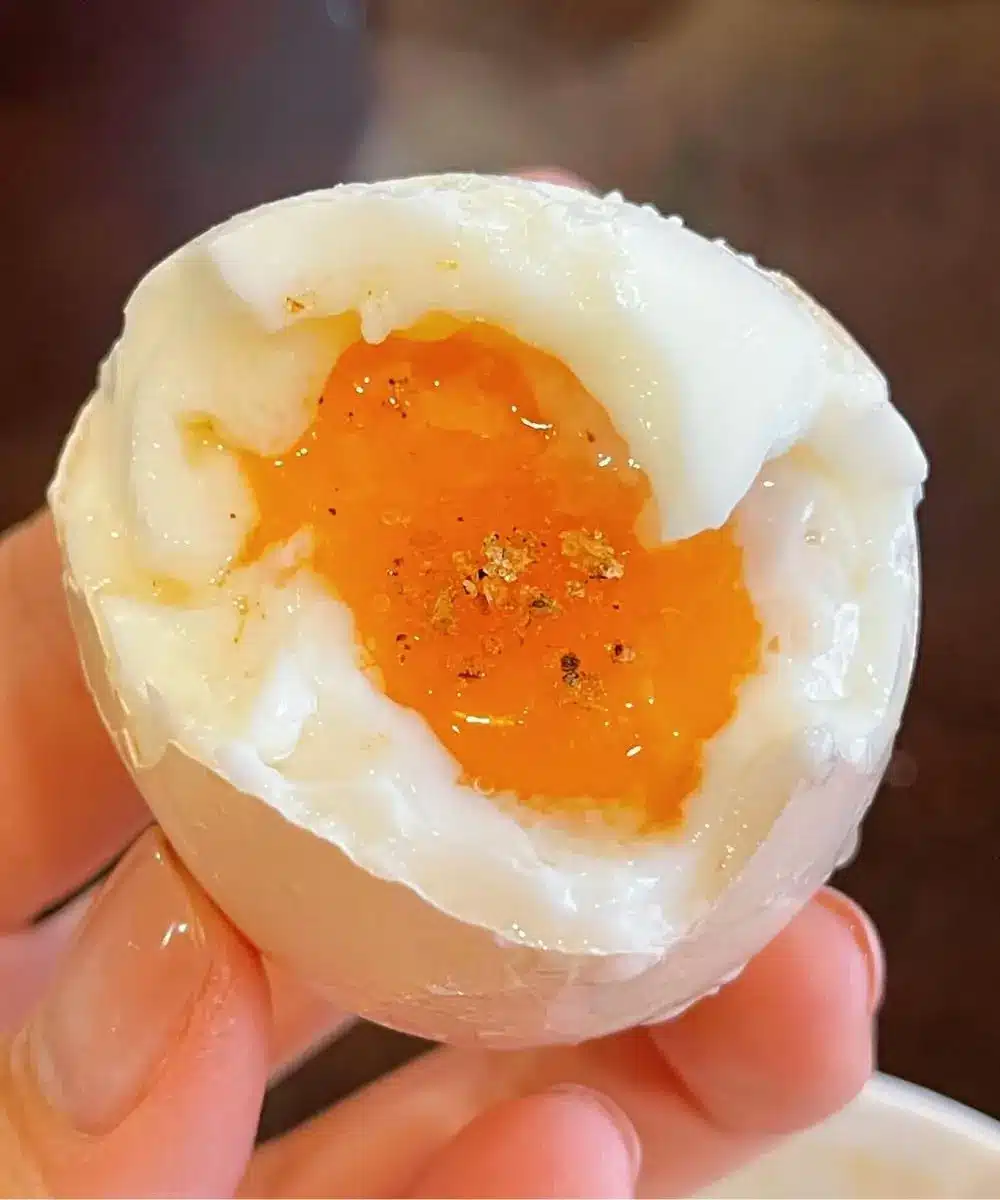 Two soft boiled eggs sliced in half on a piece of whole grain toast with sprouts and seeds