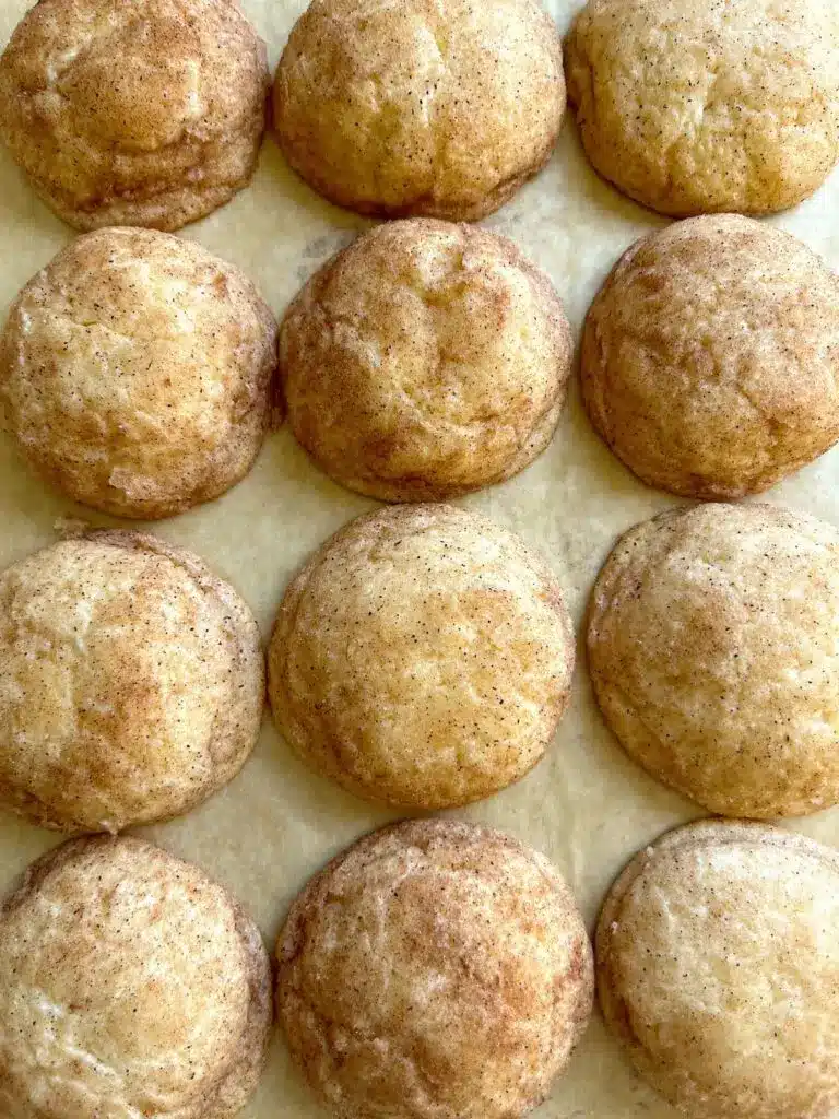 A stack of soft cinnamon cream cheese cookies on a white plate with a sprinkle of cinnamon