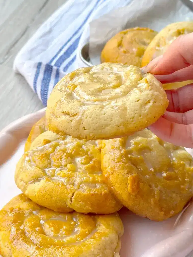 A stack of soft honey bun cookies on a white plate with a drizzle of honey.