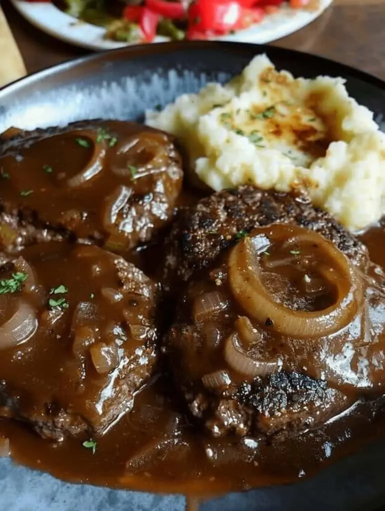 Plated hamburger steak smothered in onion gravy with a side of mashed potatoes