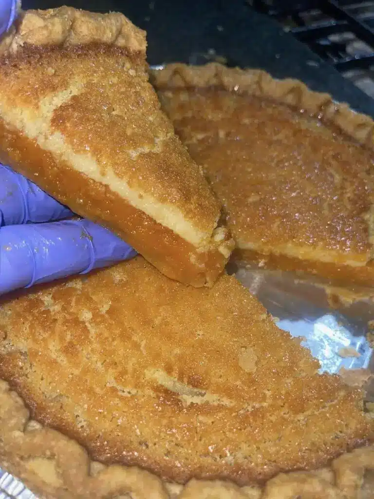 A slice of sweet potato buttermilk pie served on a plate with a dollop of whipped cream.