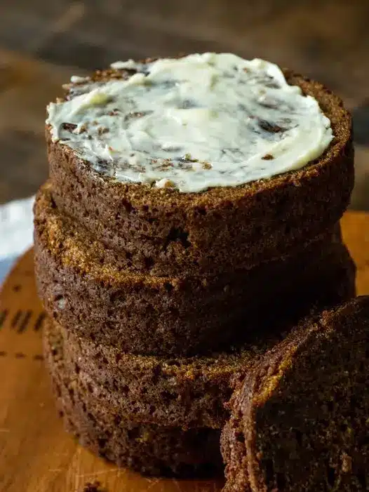 Traditional Boston brown bread served on a plate with butter and a side of baked beans