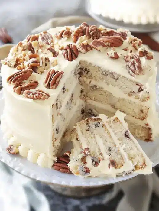 Whole Italian cream cake frosted with cream cheese and topped with pecans
