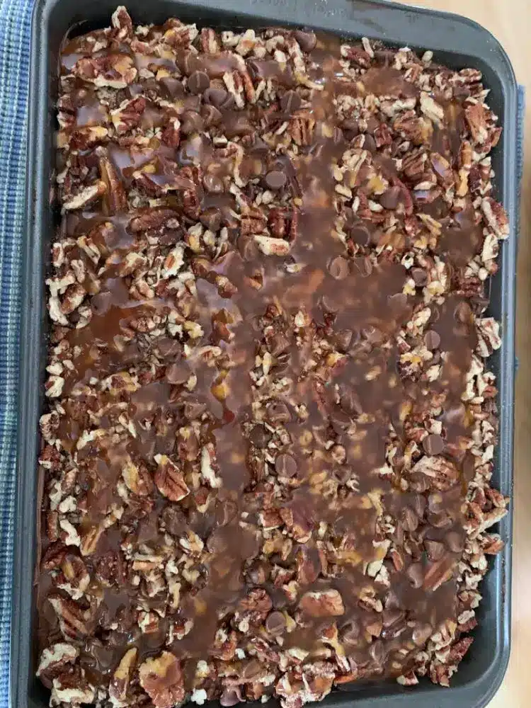 A sliced piece of turtle chocolate poke cake on a plate showing the caramel filling